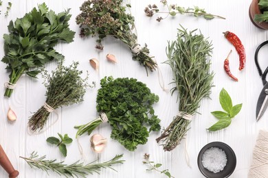 Photo of Different aromatic herbs, spool of thread and scissors on white wooden table, flat lay