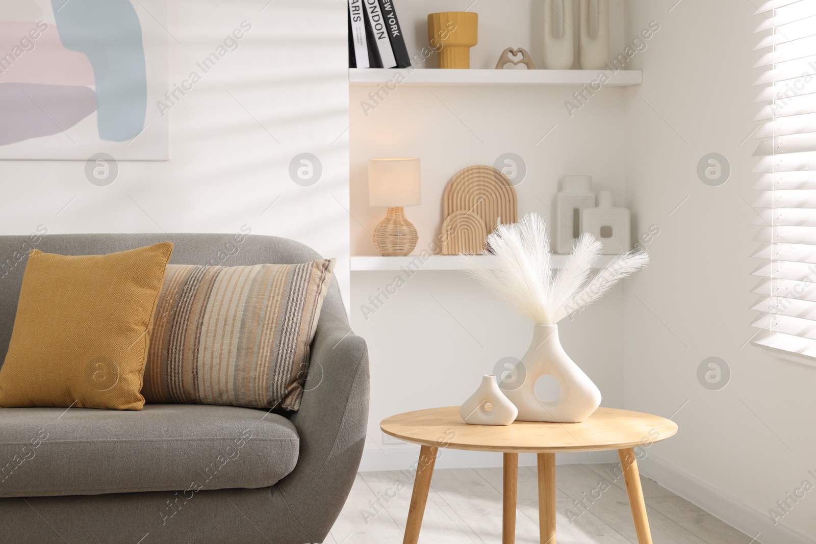 Photo of Stylish sofa with cushions and decor elements on side table in living room. Interior design