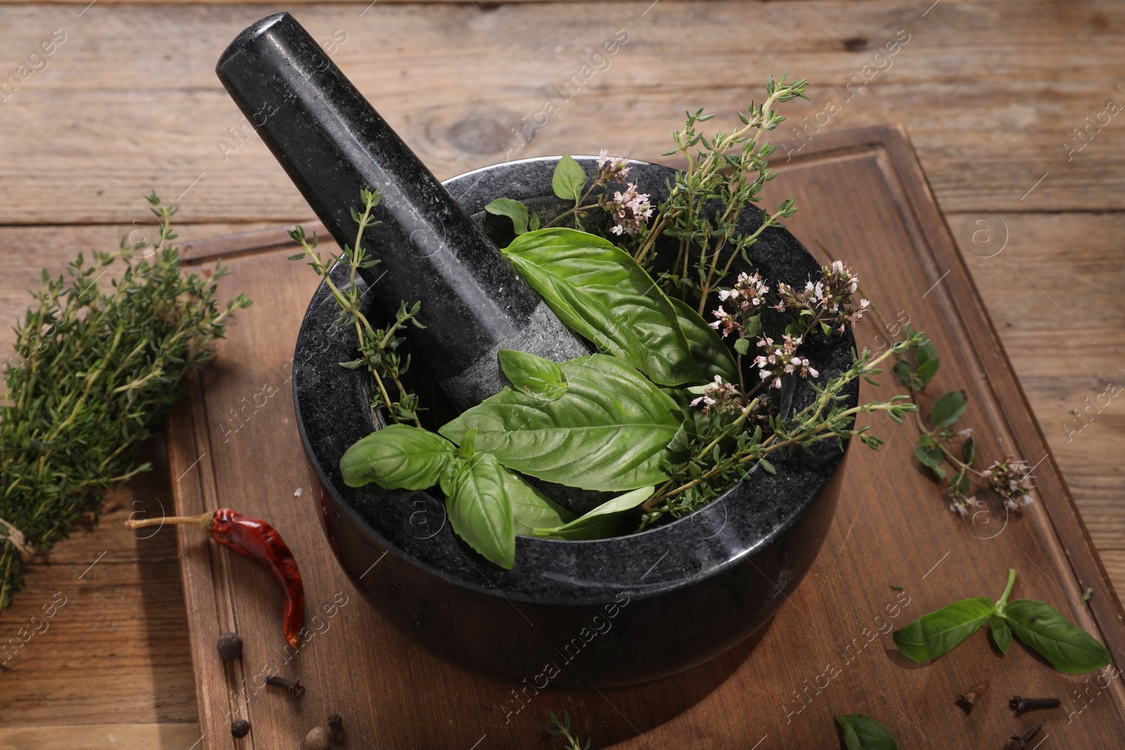 Photo of Mortar with different aromatic herbs on wooden table