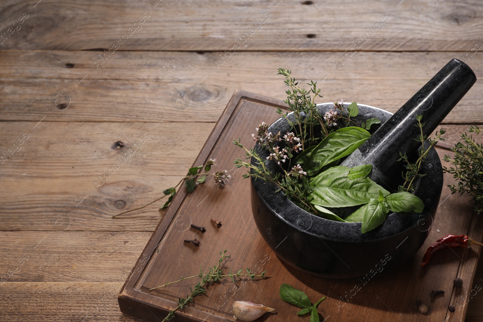 Photo of Mortar with different aromatic herbs on wooden table, space for text