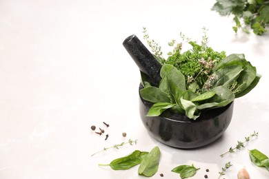 Photo of Mortar with different aromatic herbs on white table, space for text