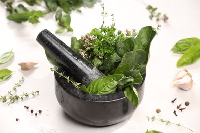 Photo of Mortar with different aromatic herbs on white table, closeup