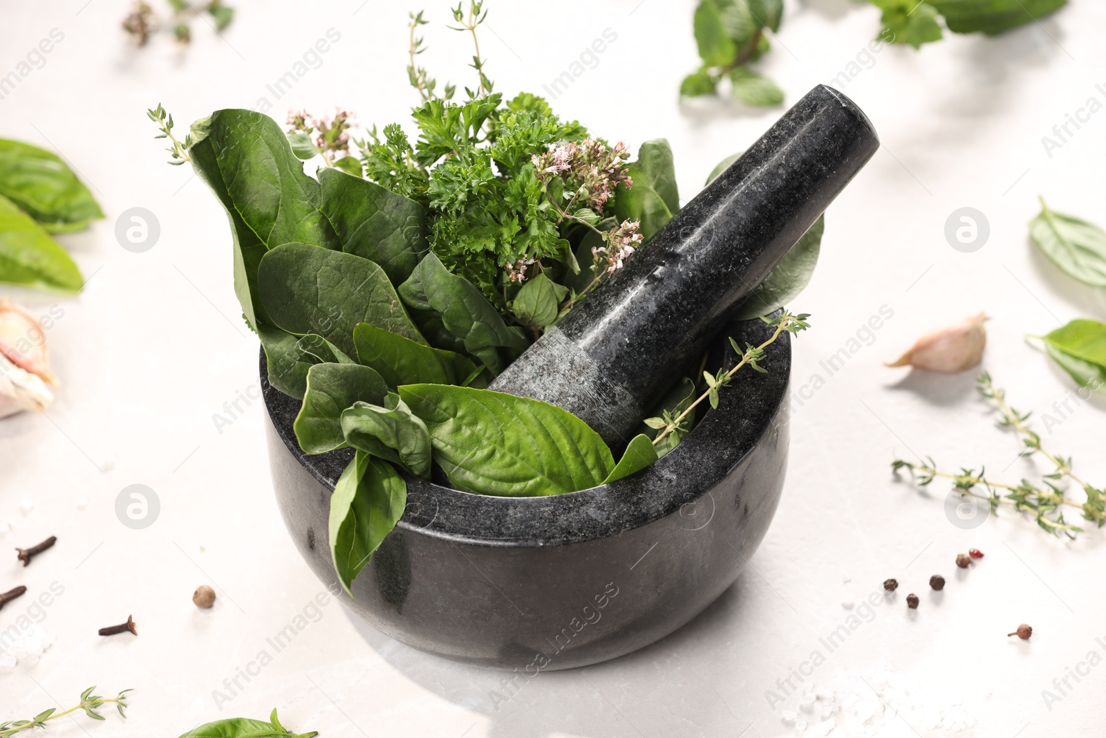 Photo of Mortar with different aromatic herbs on white table, closeup