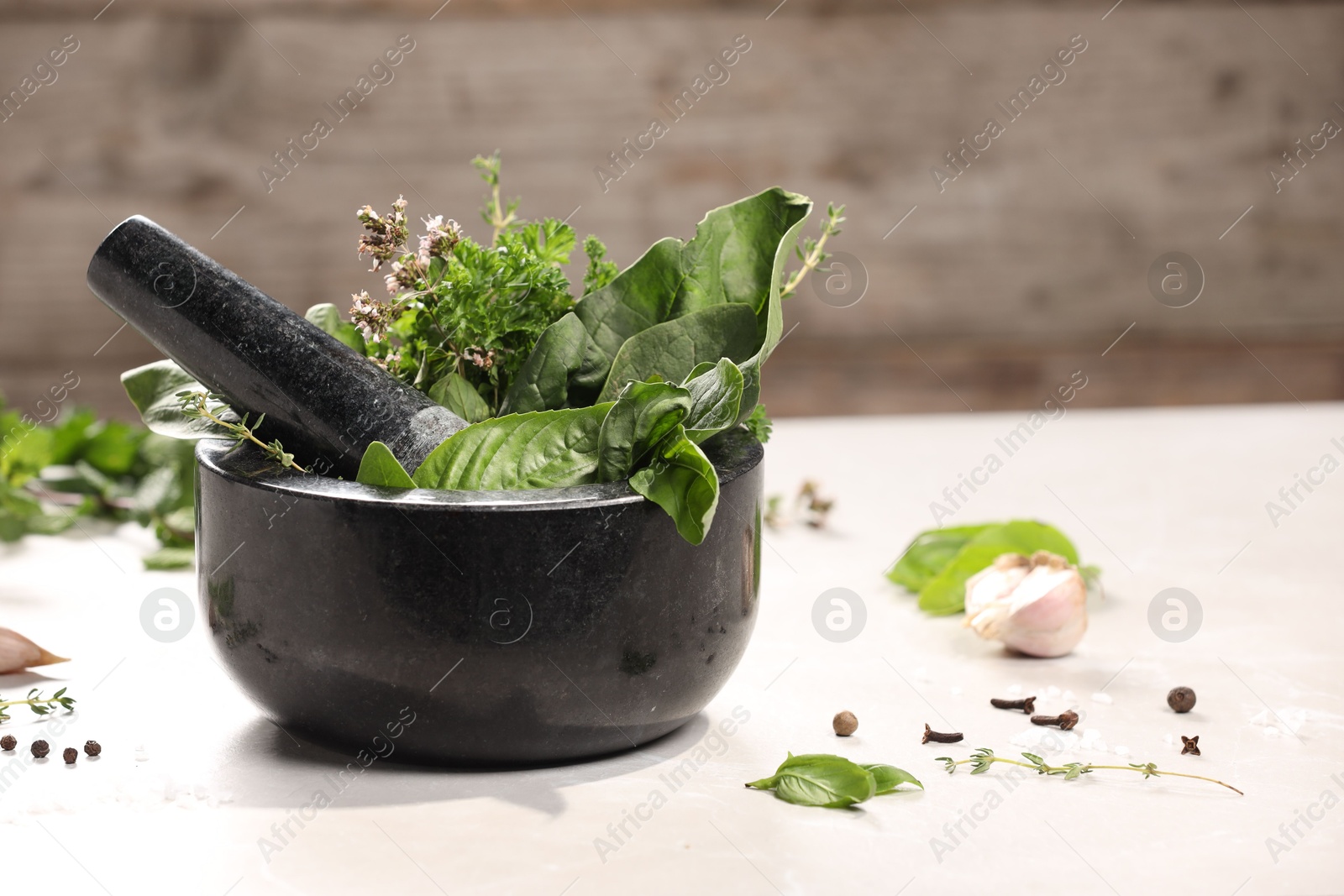 Photo of Mortar with different aromatic herbs on white table, closeup. Space for text