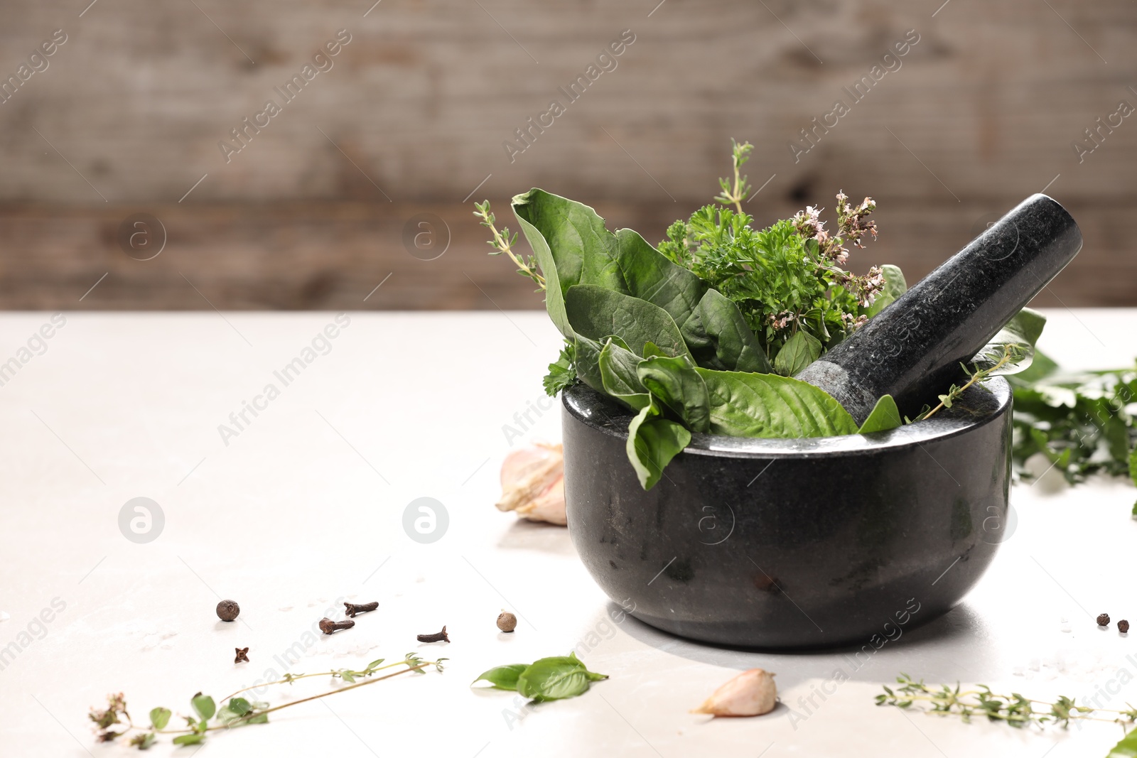 Photo of Mortar with different aromatic herbs on white table, closeup. Space for text