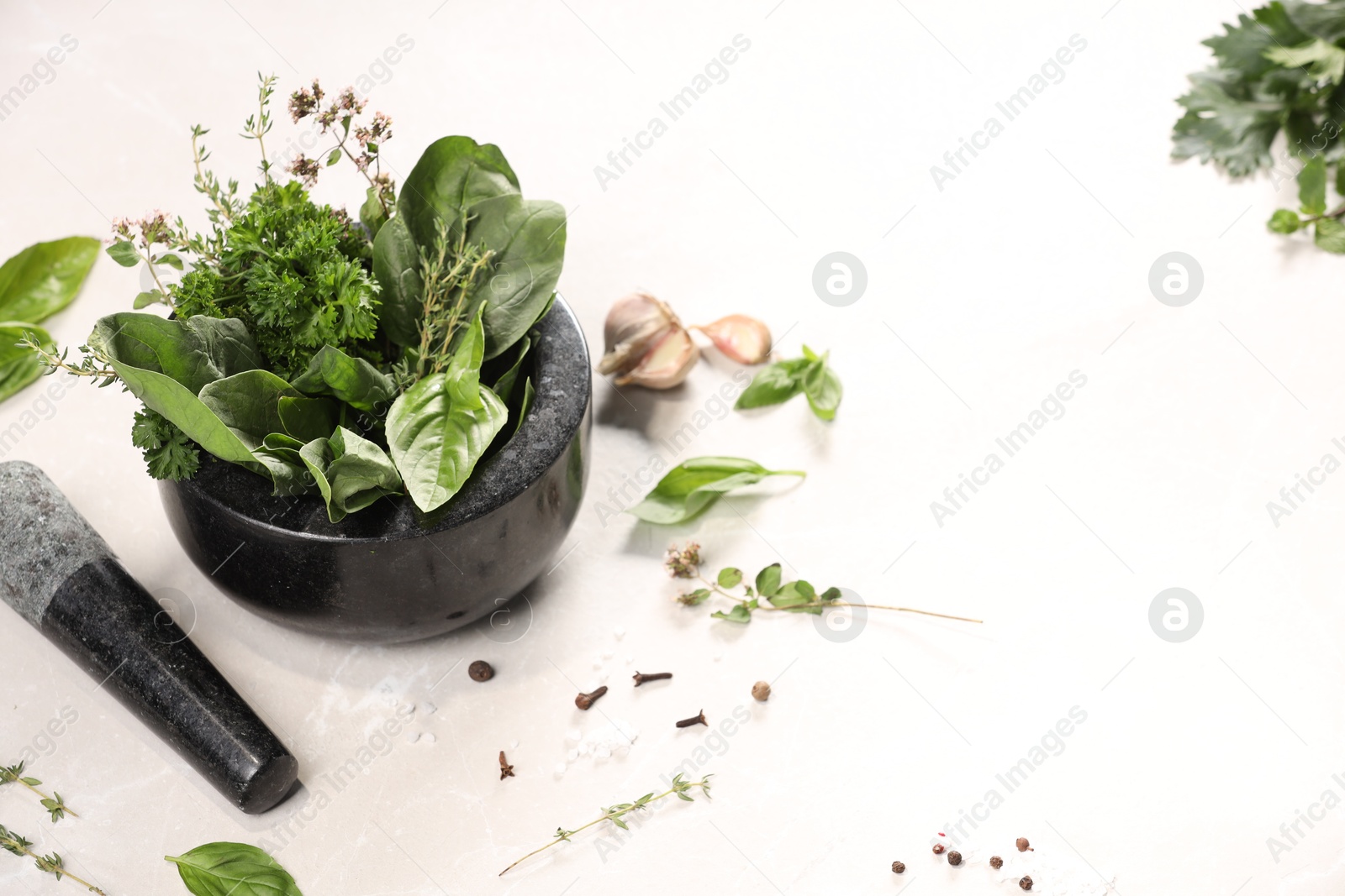 Photo of Mortar with different aromatic herbs on white table, space for text