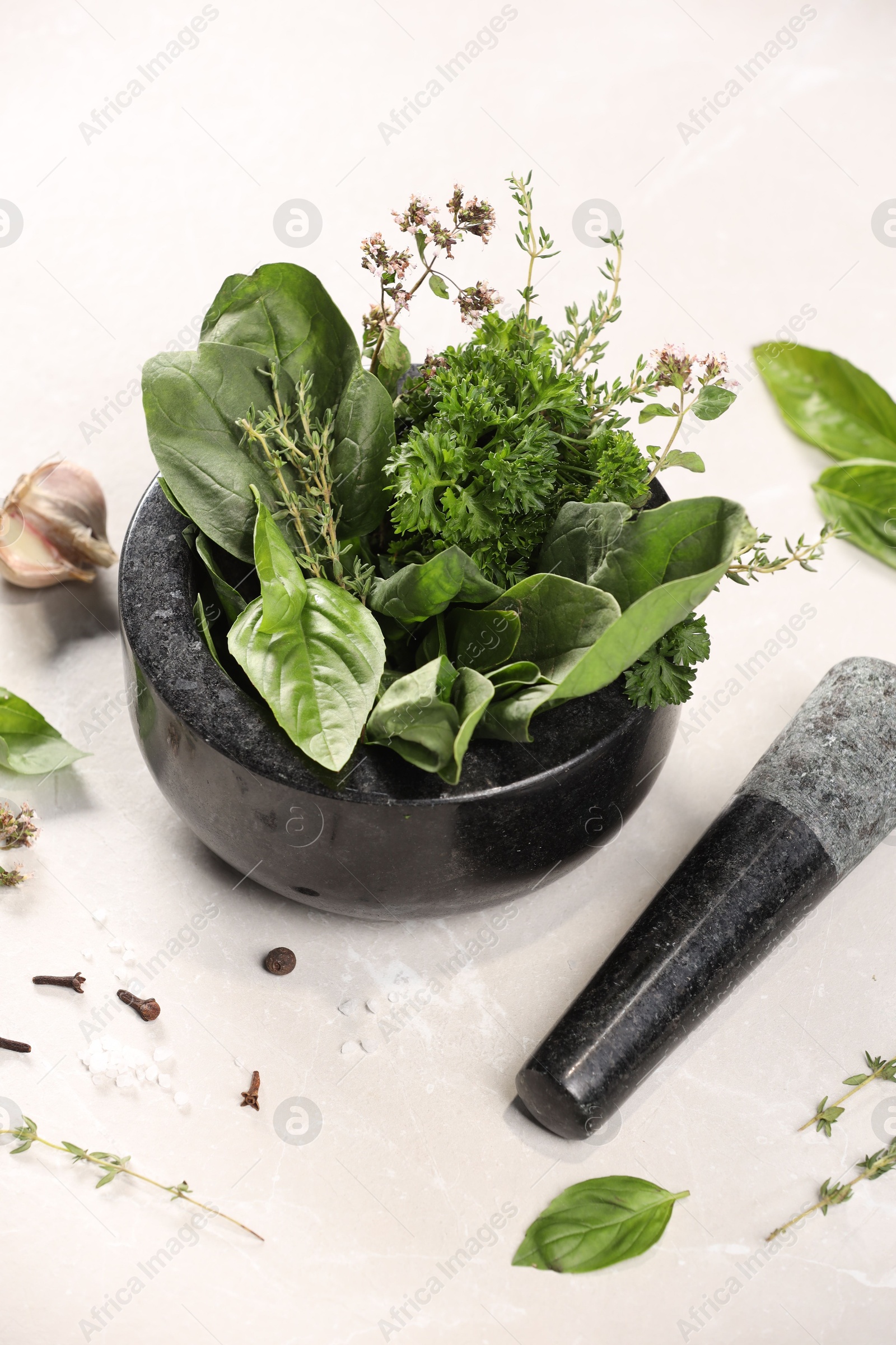 Photo of Mortar with different aromatic herbs on white table