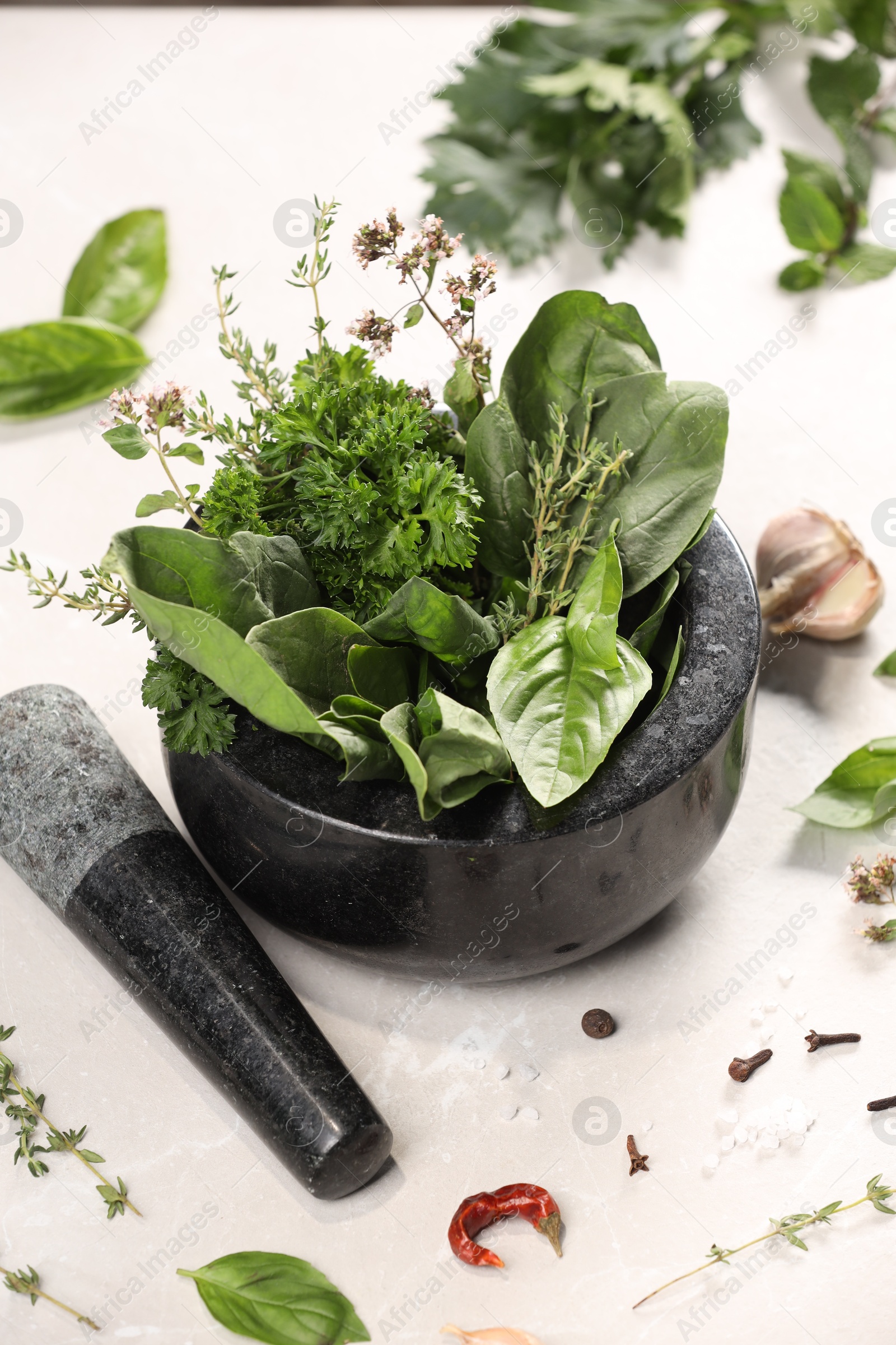 Photo of Mortar with different aromatic herbs on white table