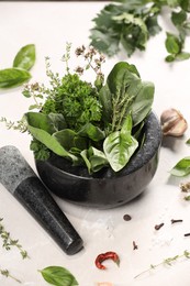 Photo of Mortar with different aromatic herbs on white table