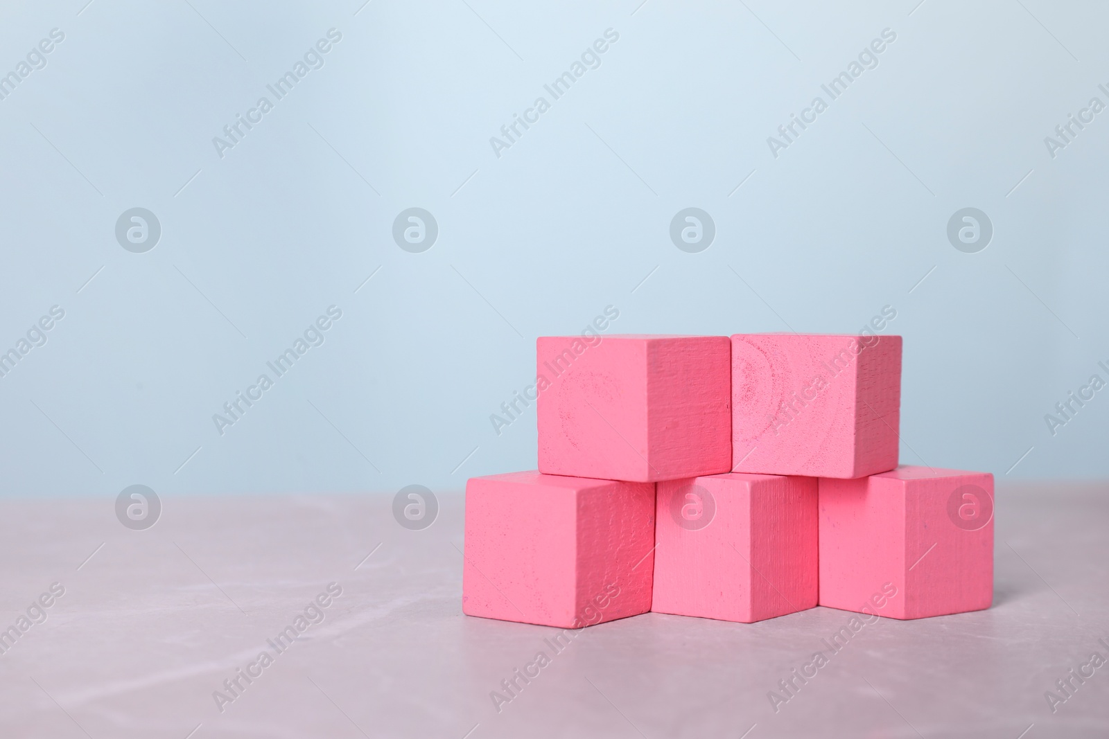 Photo of Blank pink cubes on light grey marble table, space for text