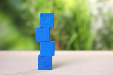 Photo of Blank blue cubes on light grey table outdoors, space for text