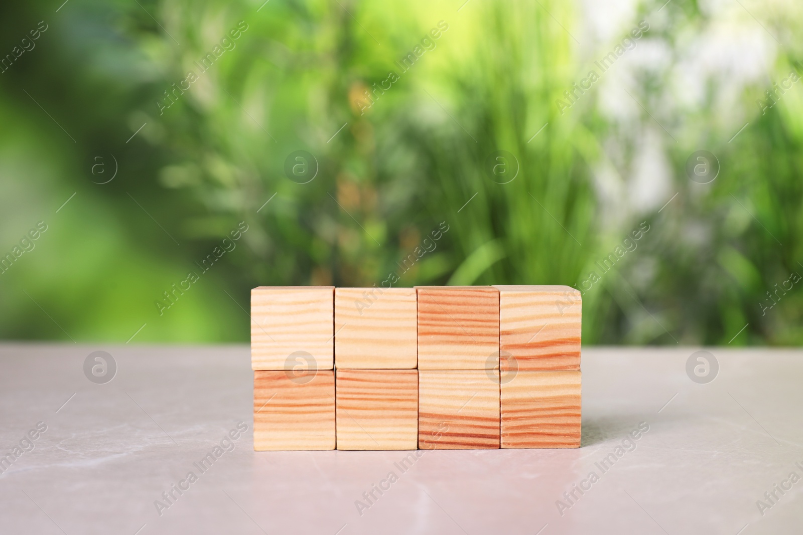 Photo of Many wooden cubes on light grey table outdoors