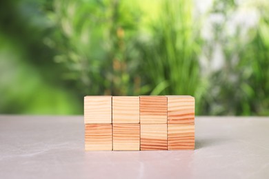 Photo of Many wooden cubes on light grey table outdoors