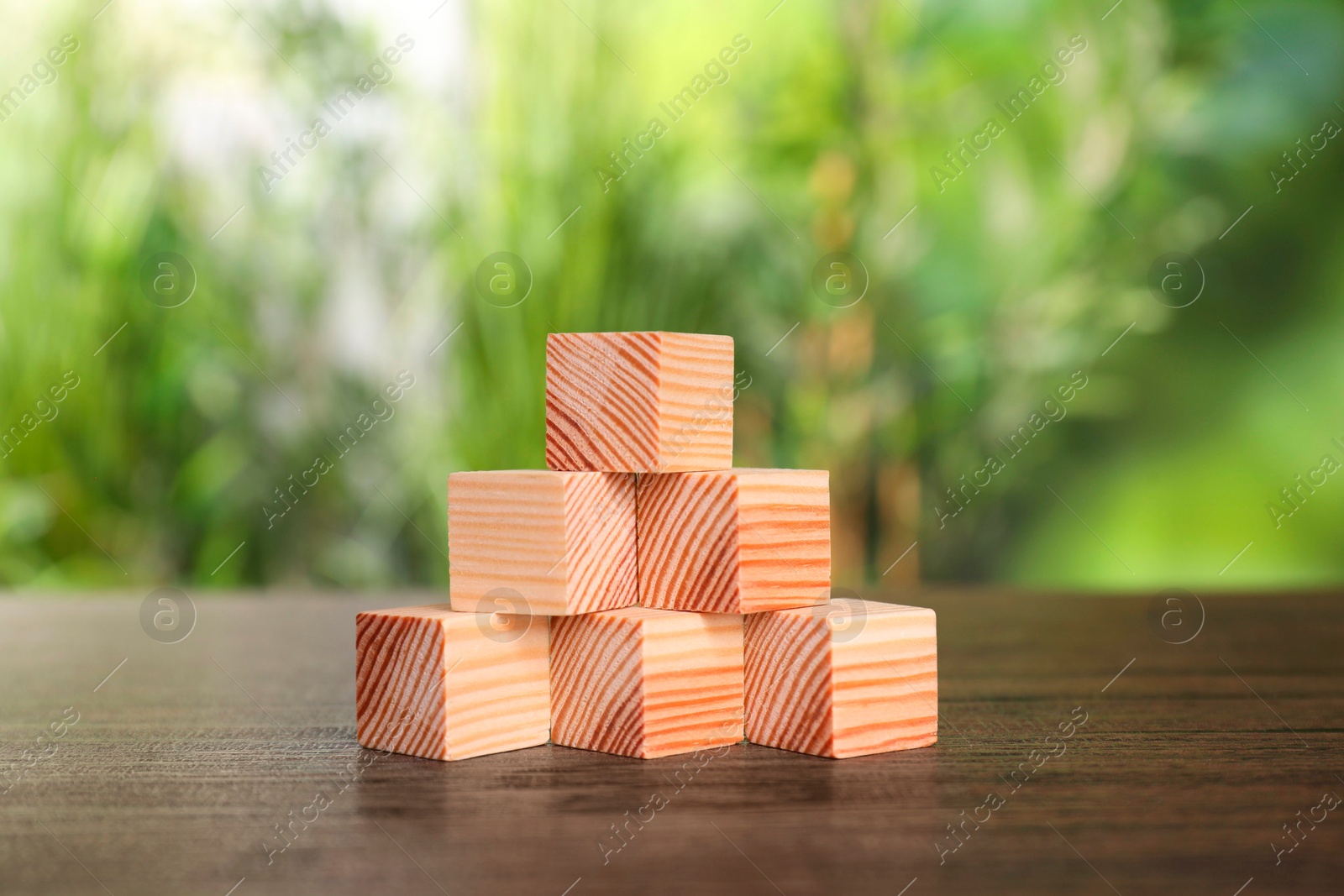 Photo of Many blank wooden cubes on table outdoors