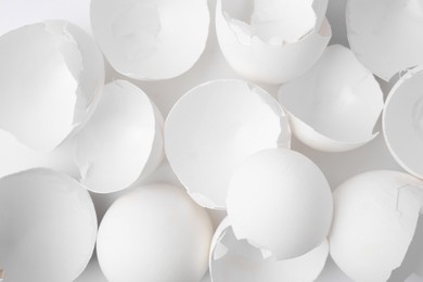 Photo of Pieces of broken eggshells on white background, top view