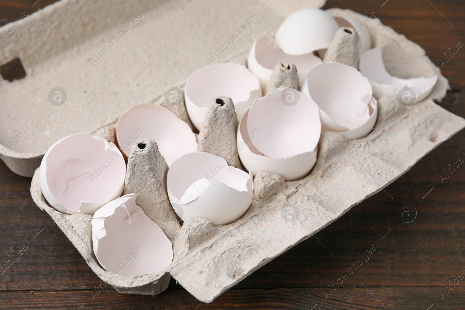 Photo of Broken eggshells in carton on wooden table, closeup