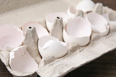 Photo of Broken eggshells in carton on table, closeup