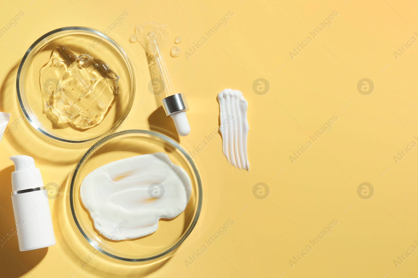 Photo of Petri dishes with cosmetic products and pipette on yellow background, flat lay. Space for text