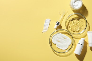 Photo of Petri dishes with cosmetic products and pipette on yellow background, flat lay. Space for text