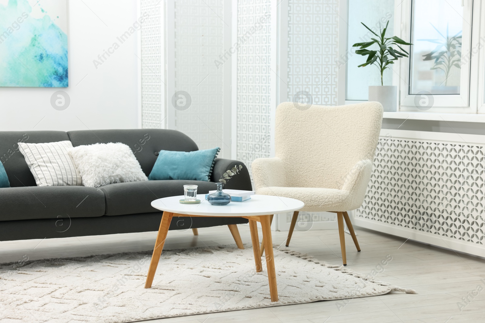 Photo of Comfortable sofa, armchair, coffee table and folding screen in living room