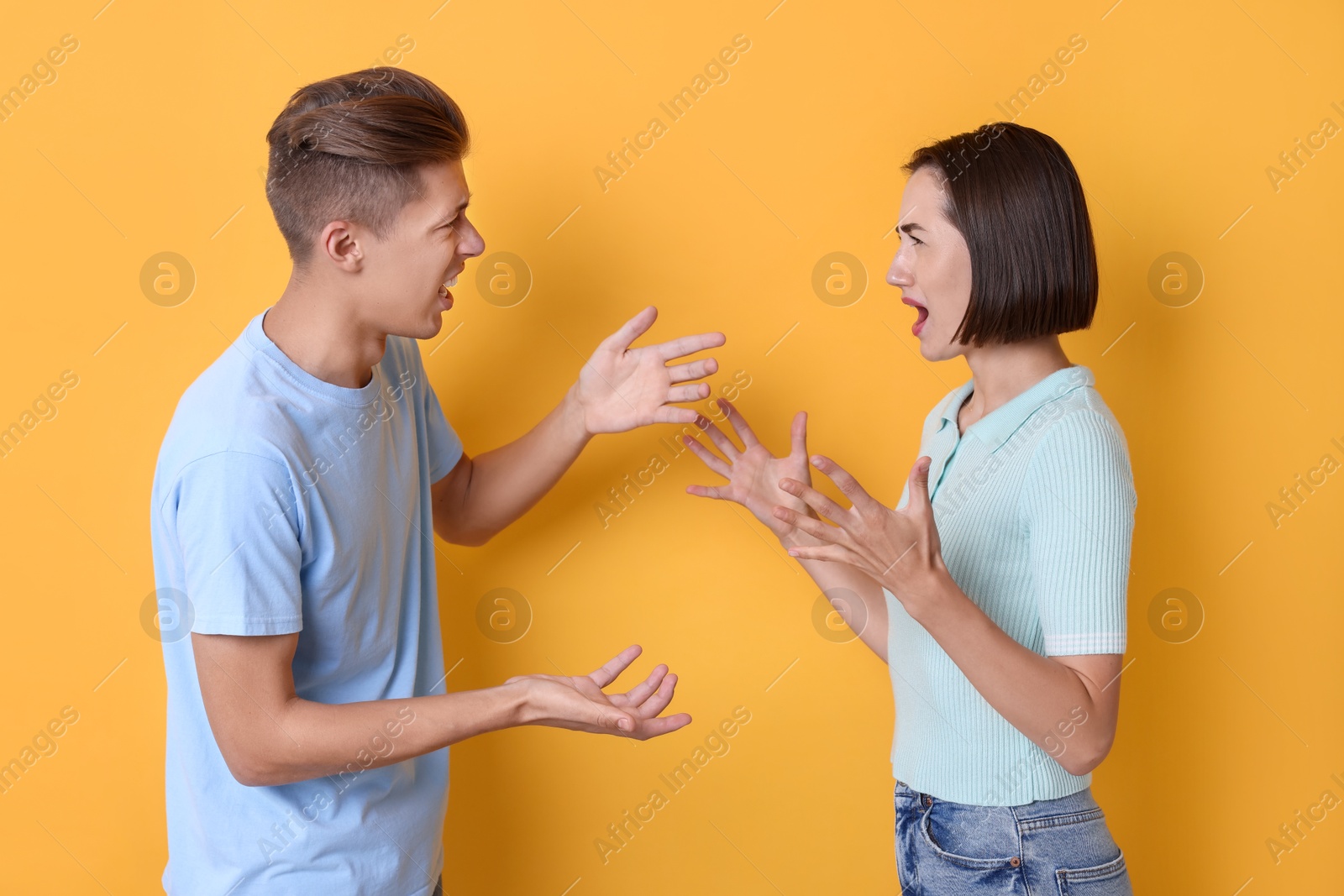 Photo of Emotional young couple arguing on orange background