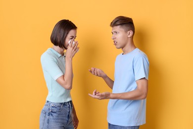 Crying woman arguing with her boyfriend on orange background