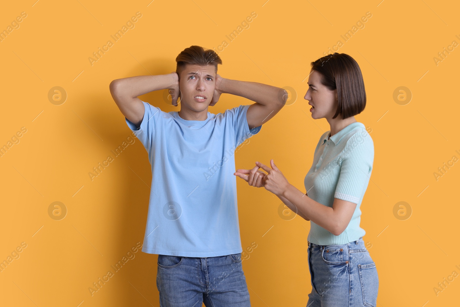 Photo of Emotional young couple arguing on orange background