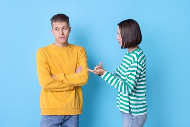 Photo of Emotional young couple having quarrel on light blue background