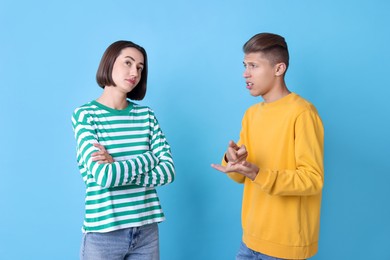 Photo of Emotional young couple having quarrel on light blue background