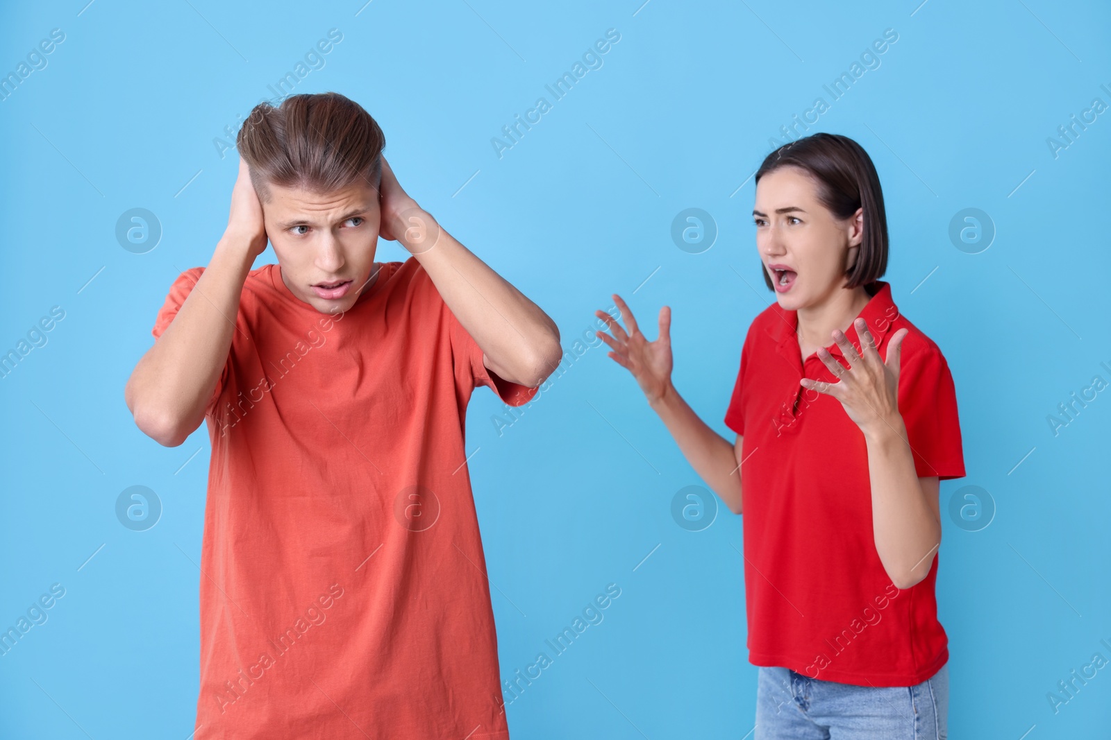 Photo of Emotional young couple having quarrel on light blue background