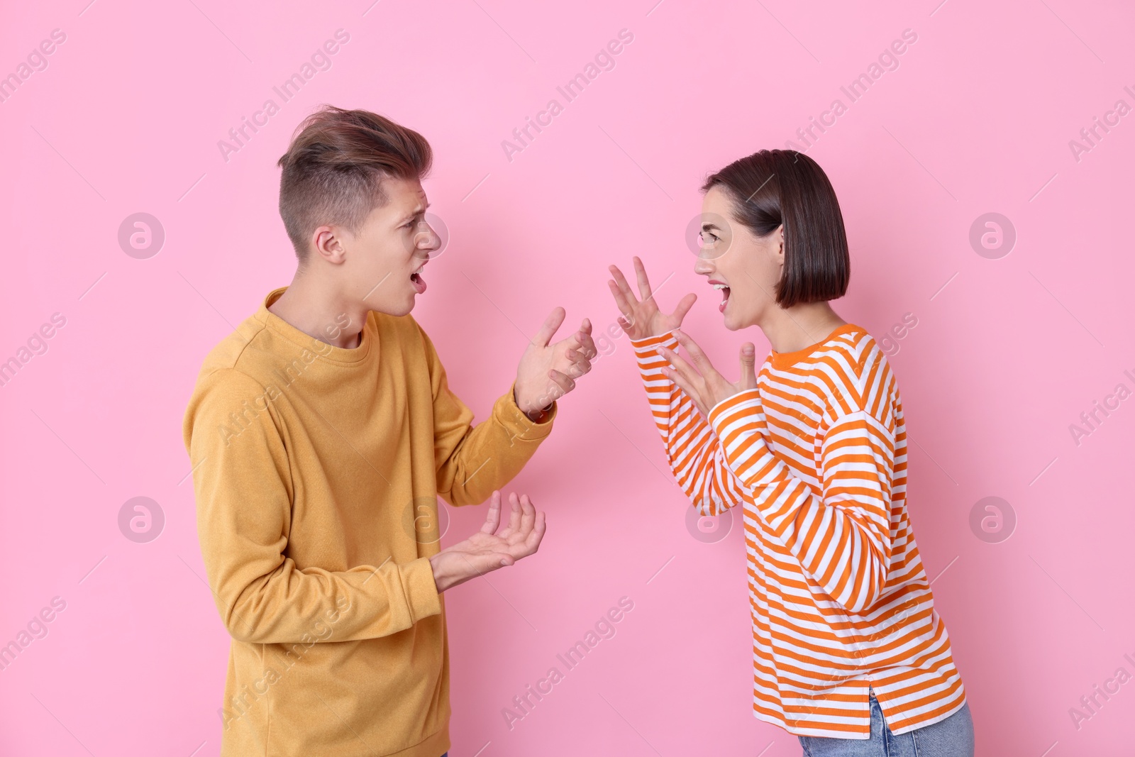 Photo of Emotional young couple arguing on pink background