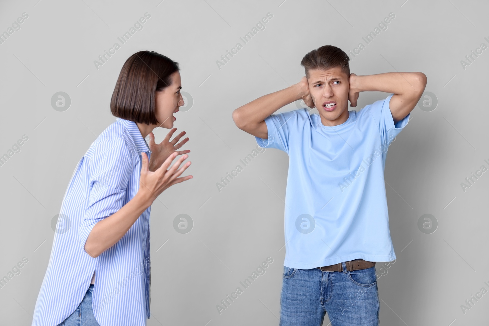 Photo of Emotional young couple having quarrel on grey background