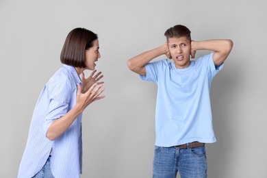 Photo of Emotional young couple having quarrel on grey background