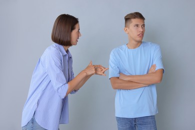 Photo of Emotional young couple having quarrel on grey background