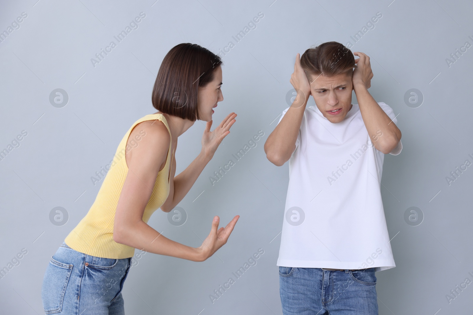 Photo of Emotional young couple having quarrel on grey background