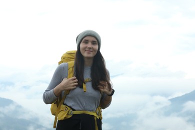 Photo of Young hiker with backpack in mountains, space for text