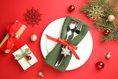 Photo of Beautiful Christmas setting with plates, elegant cutlery and festive decor on red table, flat lay