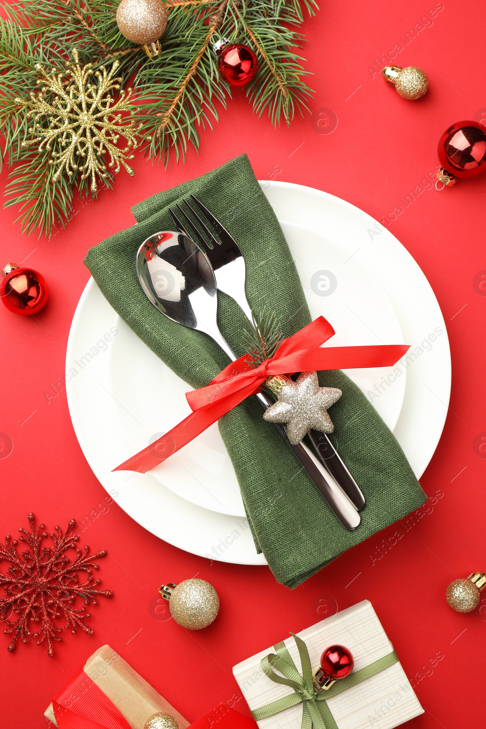 Photo of Beautiful Christmas setting with plates, elegant cutlery and festive decor on red table, flat lay