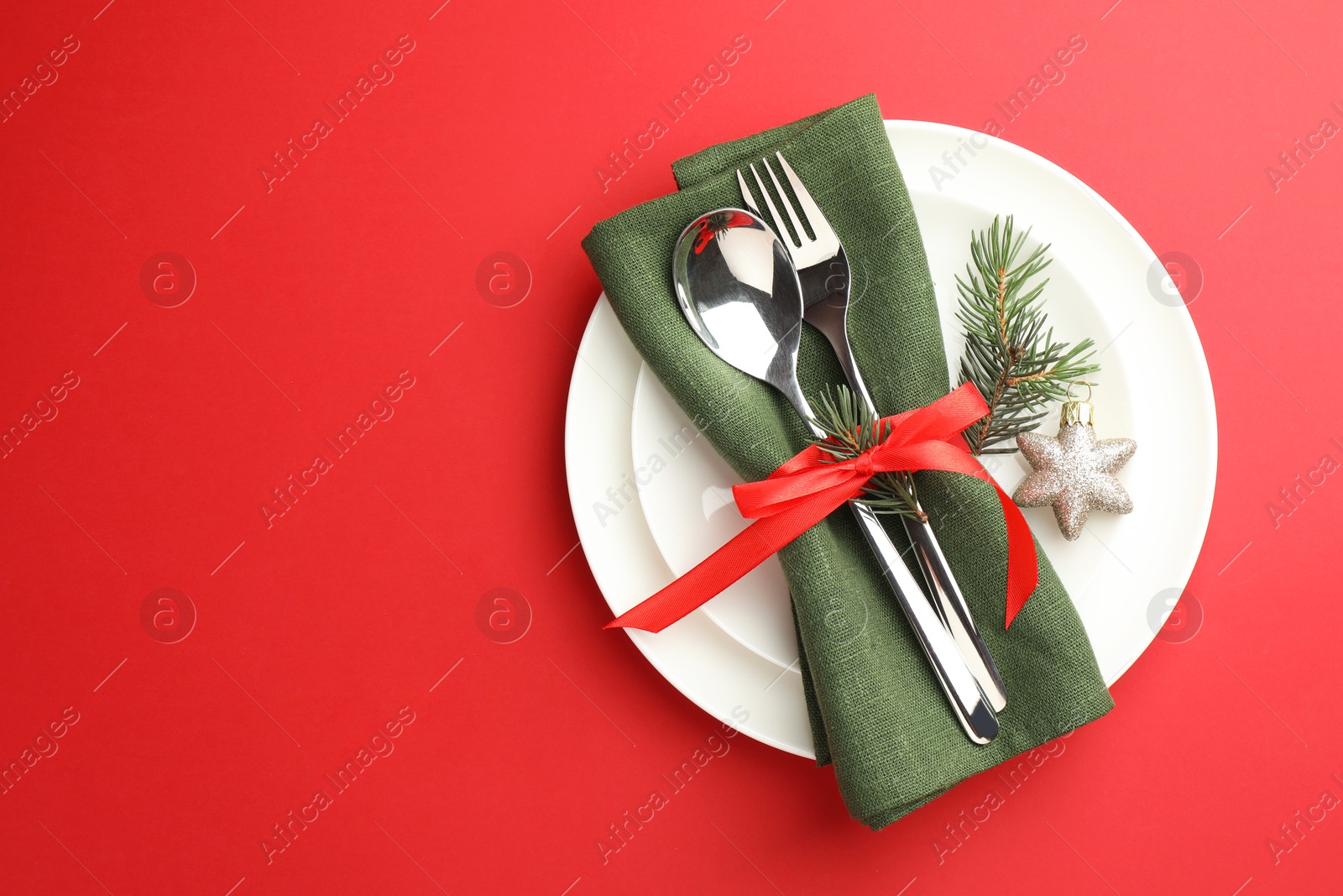 Photo of Beautiful Christmas setting with plates, elegant cutlery and festive decor on red table, top view. Space for text