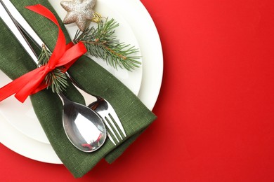 Photo of Beautiful Christmas setting with plates, elegant cutlery and festive decor on red table, top view. Space for text