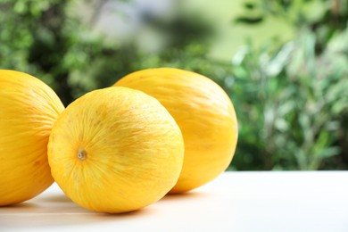 Photo of Fresh ripe melons on white table outdoors, space for text