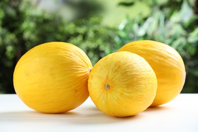 Photo of Fresh ripe melons on white table outdoors