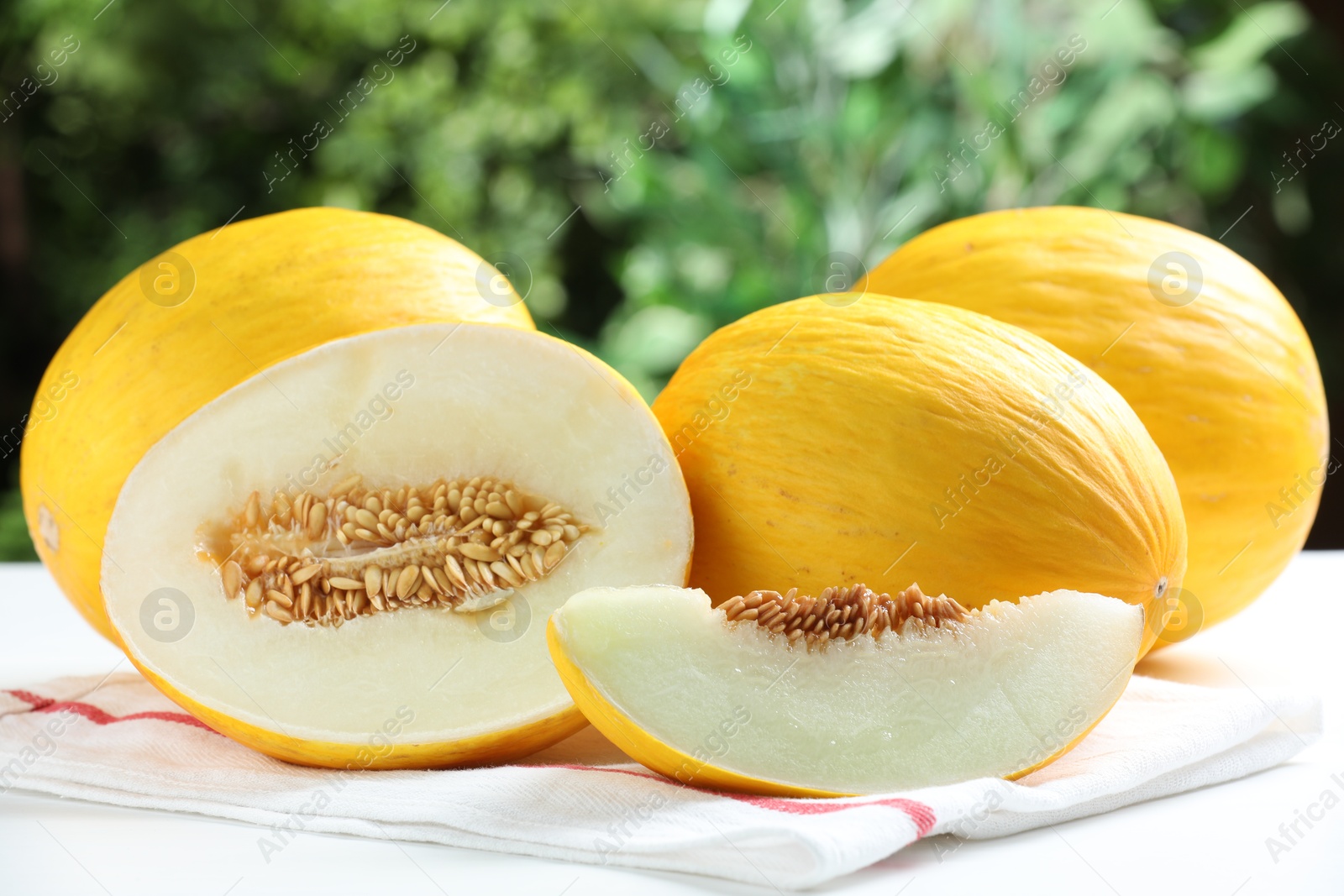 Photo of Fresh ripe melons on white table outdoors