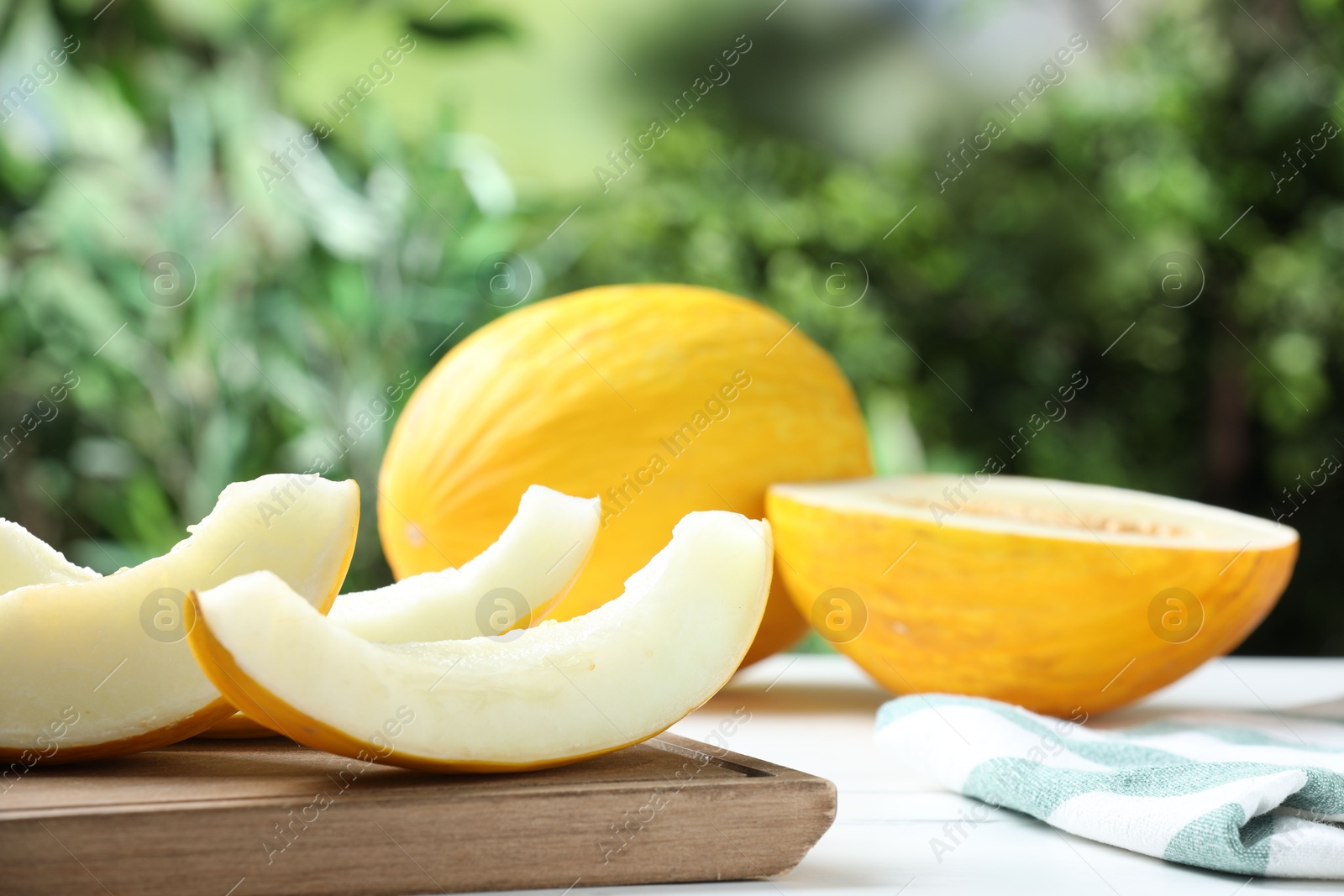 Photo of Fresh ripe melons on white table outdoors, space for text