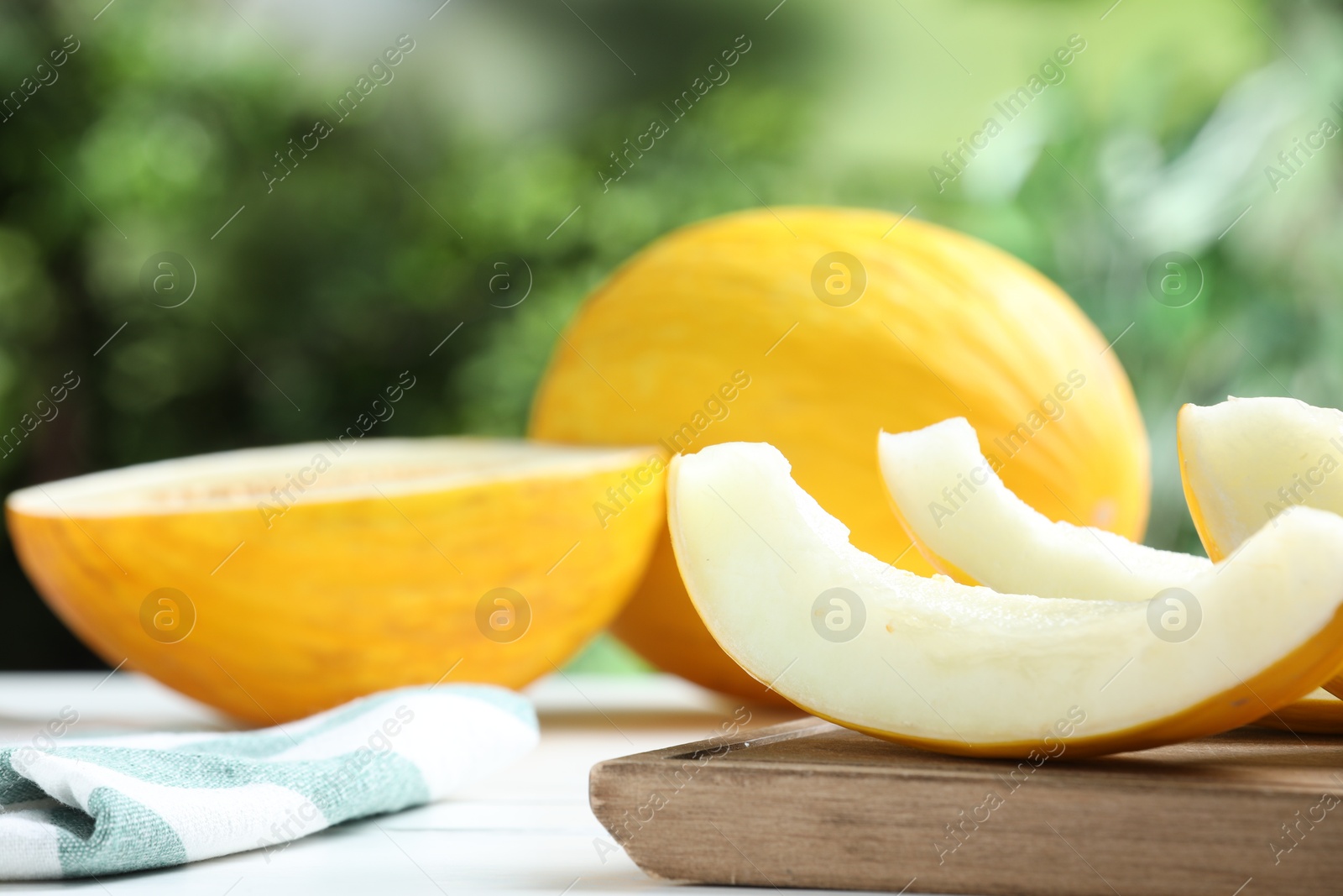 Photo of Fresh ripe melons on white table outdoors, space for text