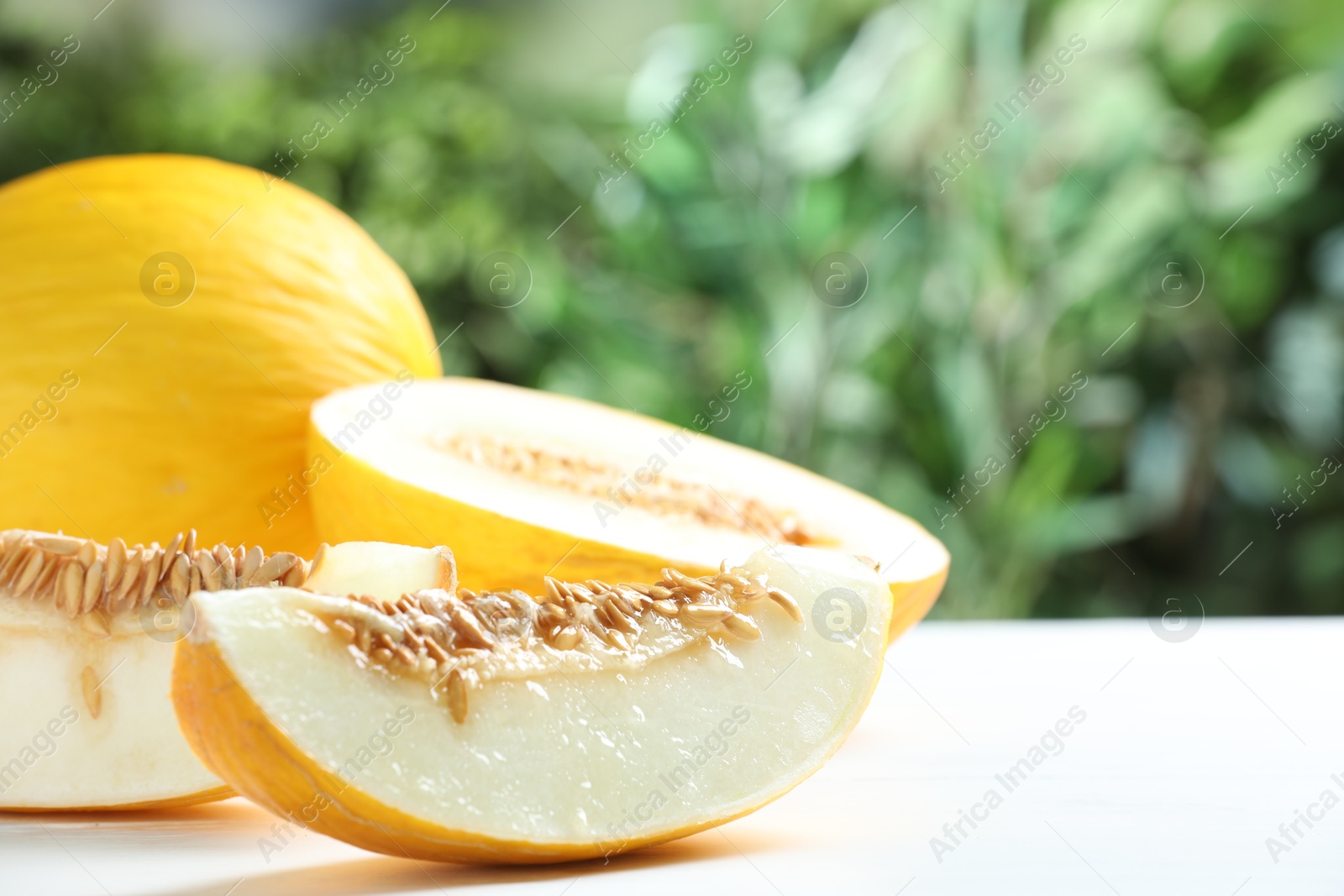 Photo of Fresh ripe melons on white table outdoors, closeup. Space for text