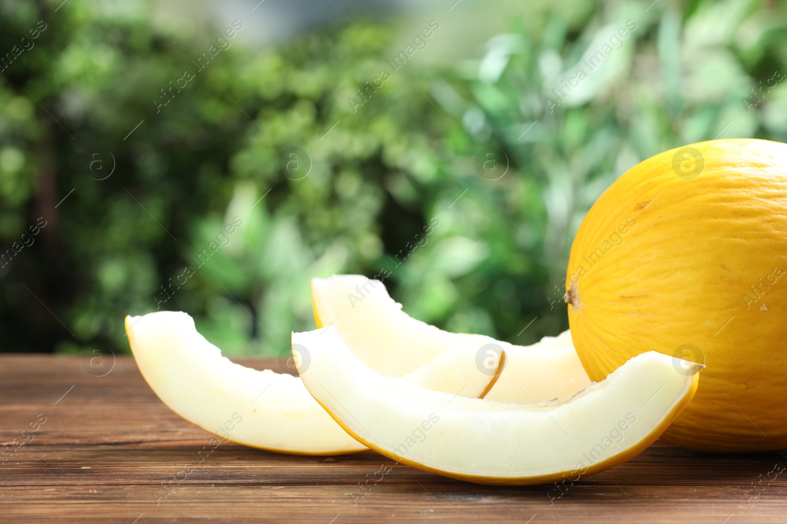 Photo of Fresh ripe melons on wooden table outdoors