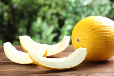 Photo of Fresh ripe melons on wooden table outdoors