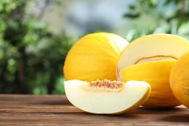 Photo of Fresh ripe melons on wooden table outdoors