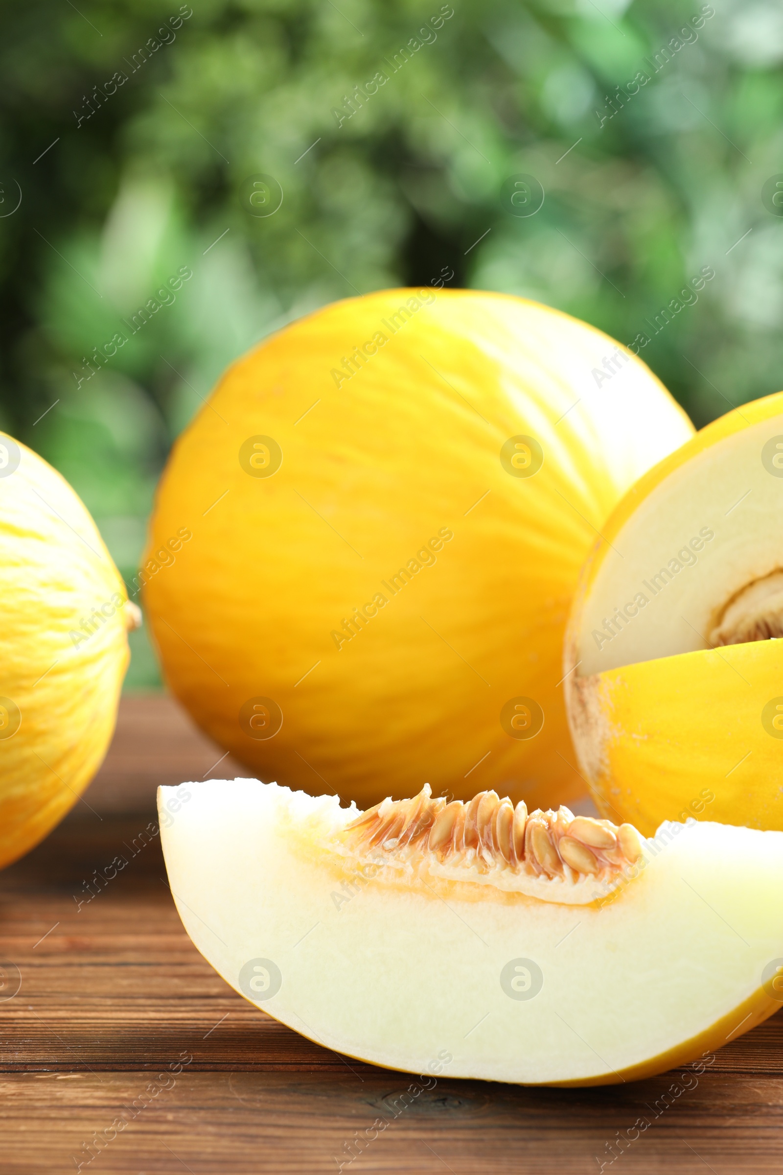 Photo of Fresh ripe melons on wooden table outdoors, closeup